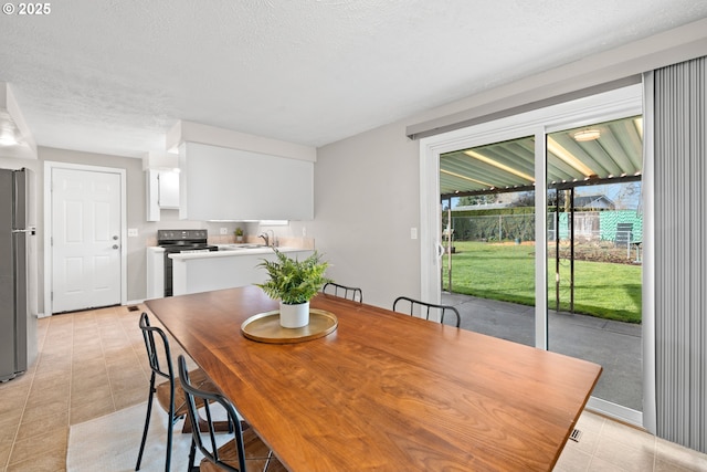 dining area featuring light tile patterned flooring and a textured ceiling