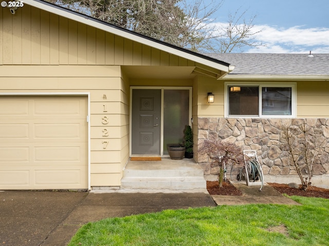 view of exterior entry featuring an attached garage, stone siding, and a shingled roof