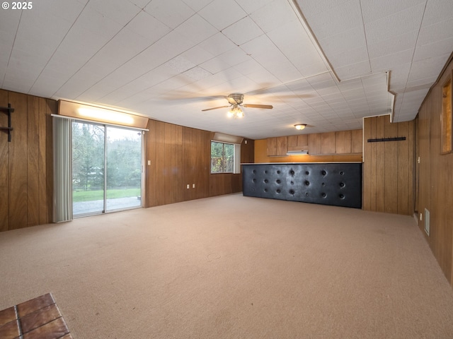 below grade area with ceiling fan, wood walls, and carpet flooring