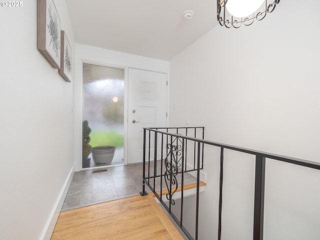 hallway featuring baseboards, an upstairs landing, and wood finished floors