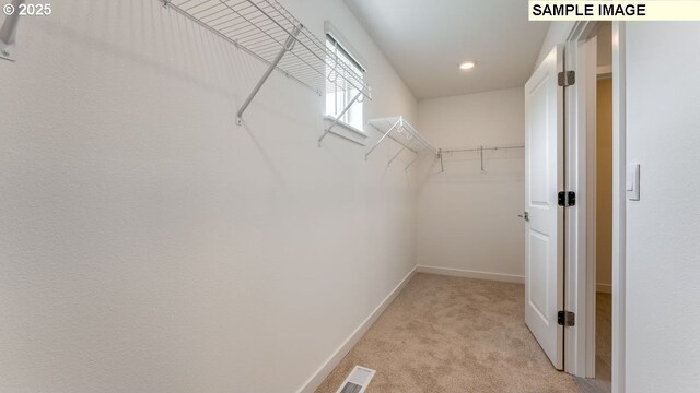 walk in closet with light colored carpet and visible vents