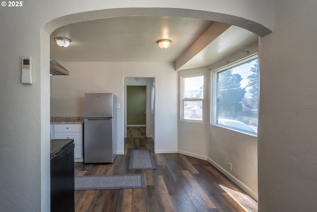 kitchen with baseboards, arched walkways, dark wood finished floors, freestanding refrigerator, and fridge