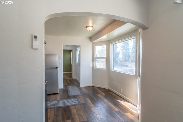 interior space with arched walkways, dark wood-style flooring, and baseboards