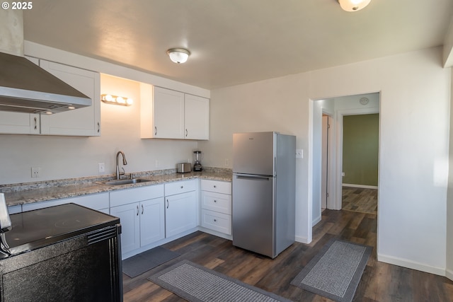 kitchen with freestanding refrigerator, white cabinets, a sink, and light stone countertops