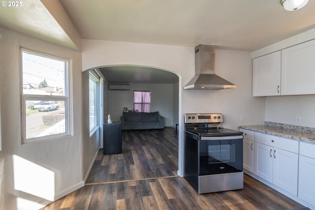 kitchen featuring stainless steel electric range oven, range hood, white cabinetry, and a wall mounted air conditioner