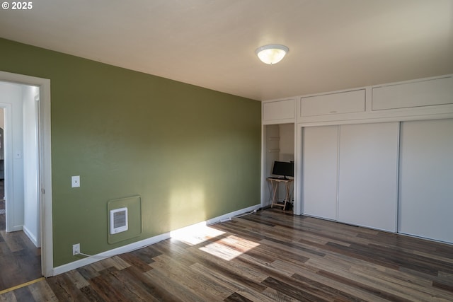 unfurnished bedroom featuring a closet, dark wood finished floors, and baseboards