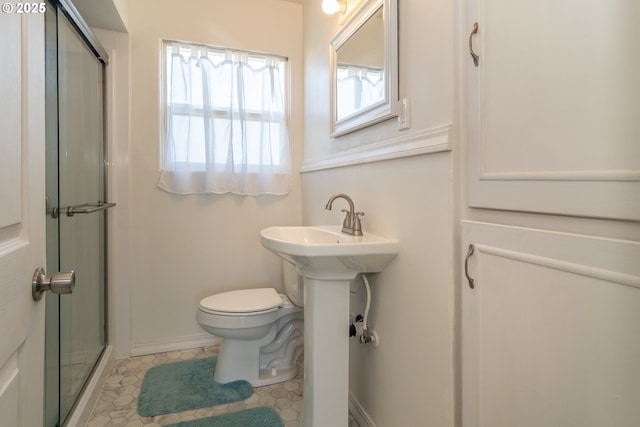 full bathroom featuring toilet, baseboards, an enclosed shower, and a sink