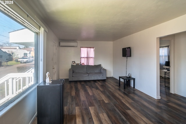 living room featuring dark wood-type flooring, a wall unit AC, and baseboards