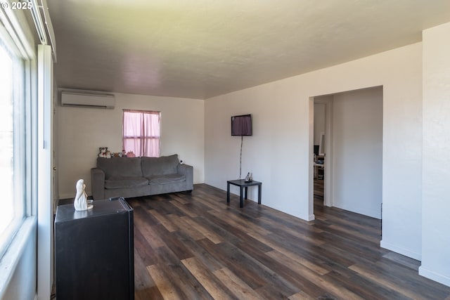 living room with a wall mounted AC and dark wood finished floors