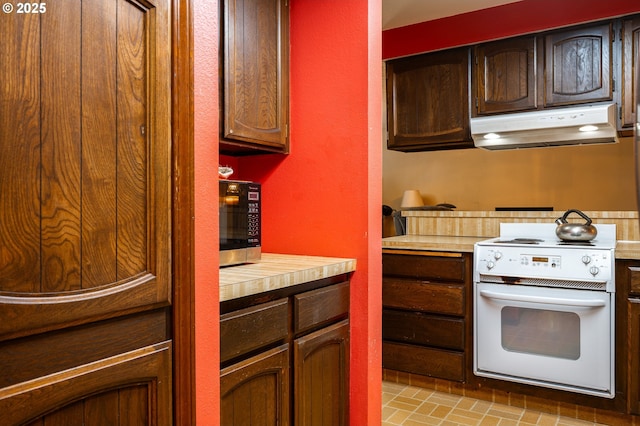 1363 SE 135th Ave, Portland, OR 97233 - kitchen featuring under cabinet range hood, electric stove, stainless steel microwave, and brick patterned flooring