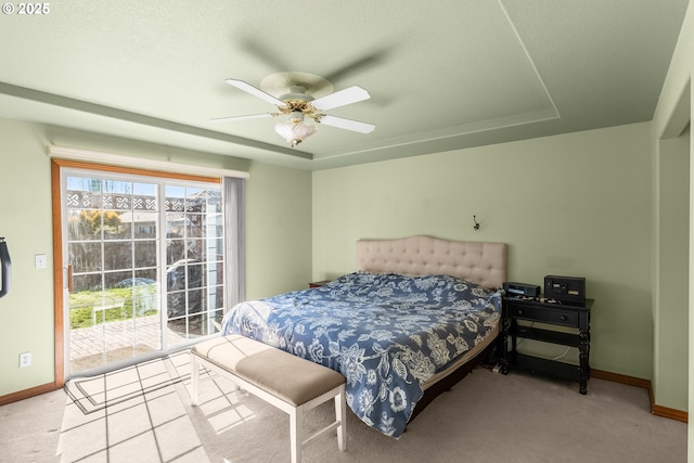 bedroom with ceiling fan, carpet floors, baseboards, access to outside, and a tray ceiling