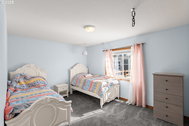 bedroom featuring baseboards, dark colored carpet, and a textured ceiling