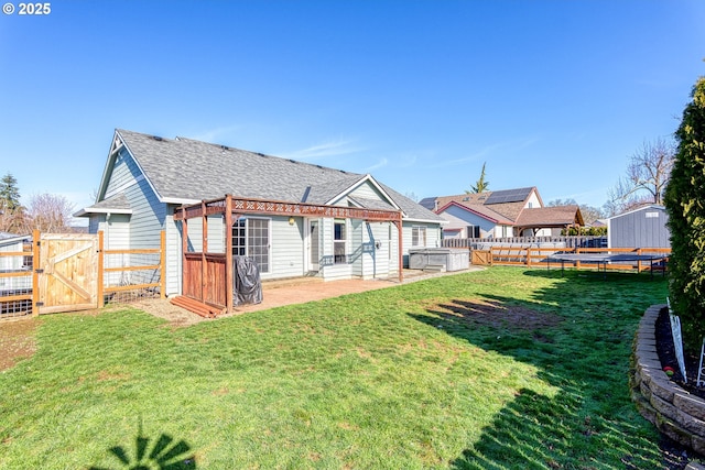 rear view of house with a fenced backyard, a gate, a trampoline, a yard, and a patio area