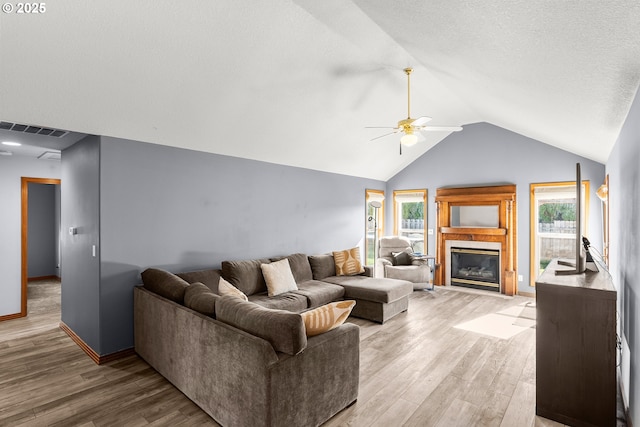 living area featuring a healthy amount of sunlight, light wood-style flooring, visible vents, and a glass covered fireplace