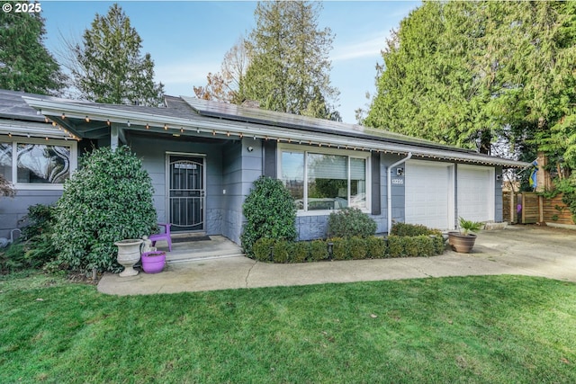 single story home featuring a garage, a front lawn, and solar panels