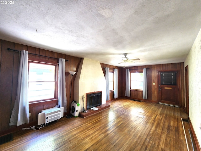 1914 1st St, La Grande, OR 97850 - unfurnished living room featuring wood finished floors, a textured ceiling, a brick fireplace, ceiling fan, and wooden walls