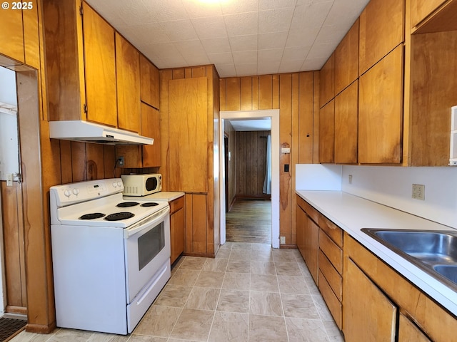 1914 1st St, La Grande, OR 97850 - kitchen featuring white appliances, under cabinet range hood, brown cabinets, light countertops, and wooden walls