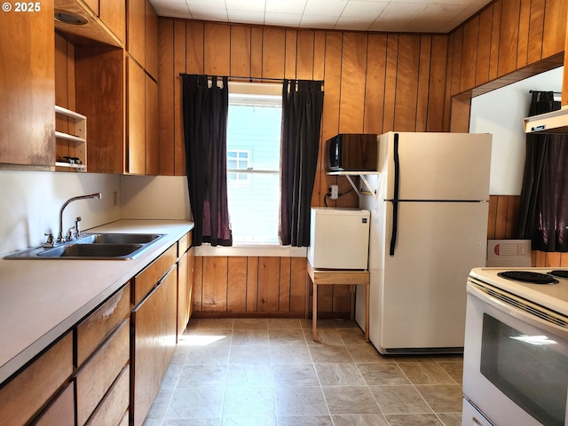 1914 1st St, La Grande, OR 97850 - kitchen featuring white appliances, a sink, brown cabinetry, wood walls, and light countertops