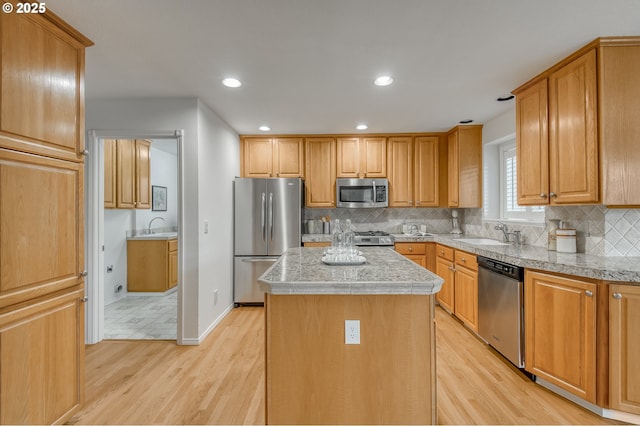 kitchen featuring sink, a kitchen island, light hardwood / wood-style floors, and appliances with stainless steel finishes