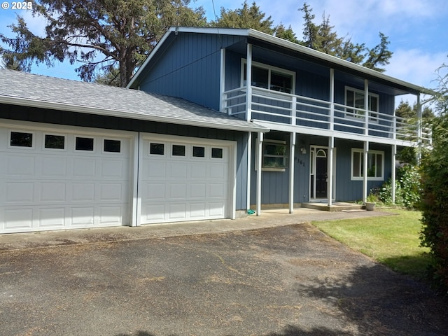 view of front of home featuring a balcony, roof with shingles, a garage, and driveway