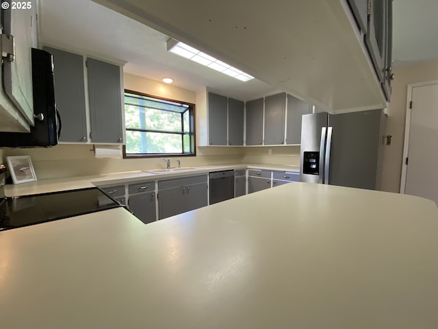 kitchen with light countertops, stainless steel appliances, a sink, and gray cabinets