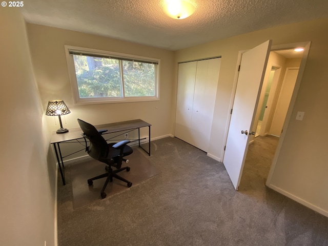office space with a textured ceiling, dark colored carpet, and baseboards