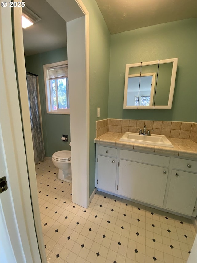 full bath with toilet, vanity, tile patterned floors, and baseboards