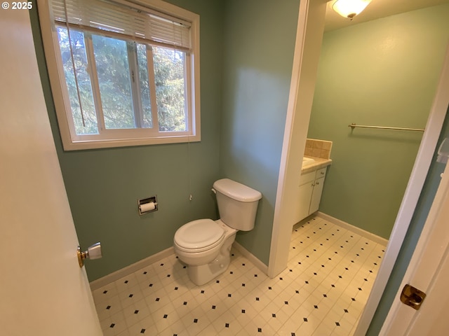 half bath featuring toilet, baseboards, and vanity