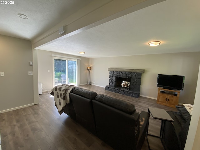 living room with a textured ceiling, baseboards, wood finished floors, and a fireplace