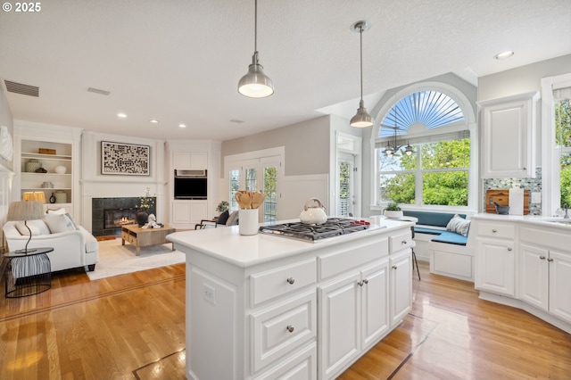 1365 NW 96th Ave, Portland, OR 97229 - kitchen with stainless steel gas cooktop, a tiled fireplace, light wood-type flooring, a center island, and open floor plan
