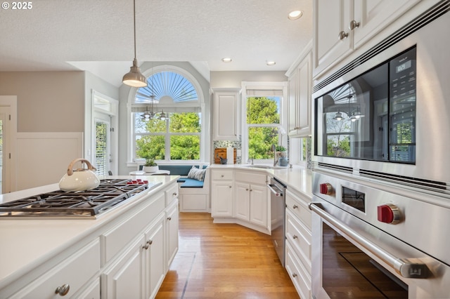 1365 NW 96th Ave, Portland, OR 97229 - kitchen with appliances with stainless steel finishes, light countertops, white cabinets, light wood-style flooring, and a sink