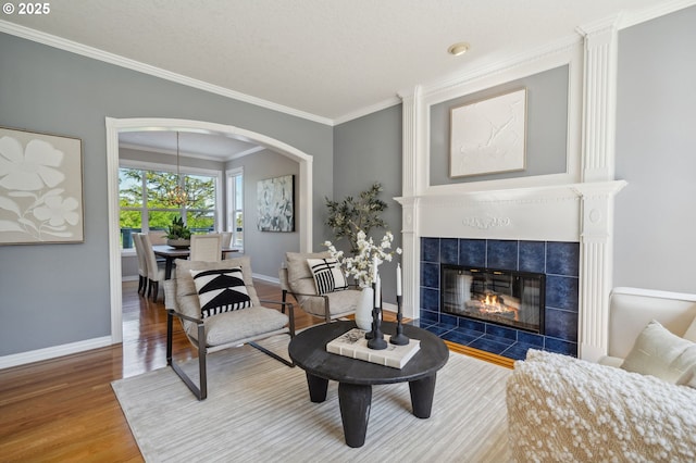 1365 NW 96th Ave, Portland, OR 97229 - living area featuring wood finished floors, ornamental molding, baseboards, a tiled fireplace, and arched walkways