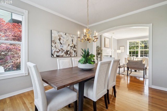 1365 NW 96th Ave, Portland, OR 97229 - dining space with crown molding, light wood finished floors, baseboards, a chandelier, and arched walkways