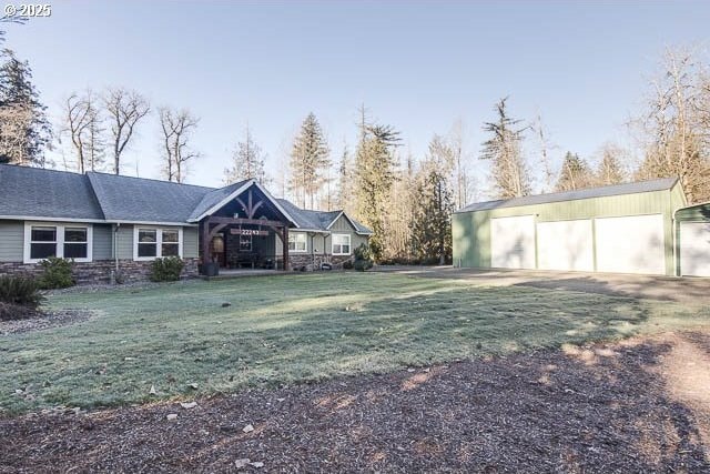 view of front of house featuring a garage, an outdoor structure, and a front lawn