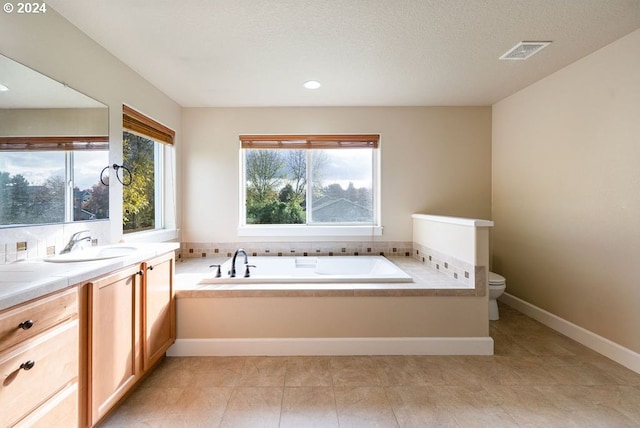 bathroom with vanity, a tub to relax in, toilet, and a textured ceiling