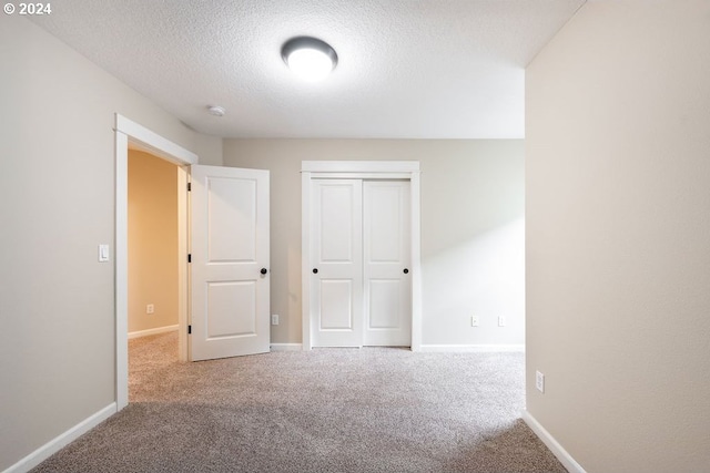 unfurnished bedroom with carpet, a textured ceiling, and a closet