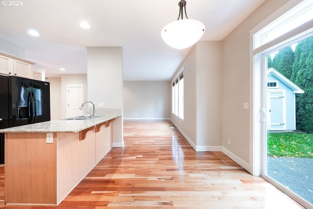 kitchen featuring a breakfast bar, sink, decorative light fixtures, light wood-type flooring, and kitchen peninsula