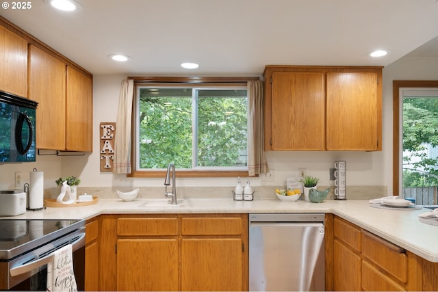 kitchen featuring appliances with stainless steel finishes, light countertops, a sink, recessed lighting, and a peninsula