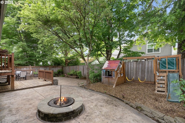 view of patio / terrace with an outdoor fire pit, a playground, a fenced backyard, and outdoor dining area