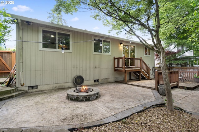 rear view of property featuring crawl space, a fire pit, a patio, a deck, and fence