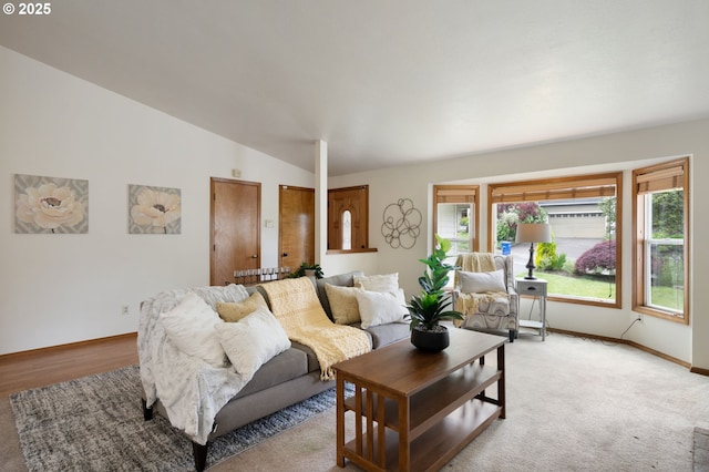 living room featuring vaulted ceiling, baseboards, and light carpet