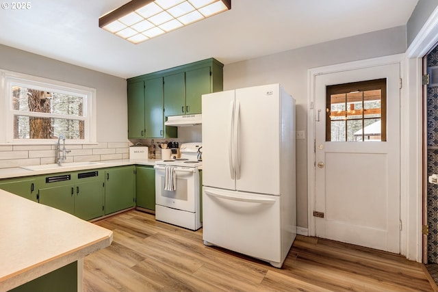 kitchen featuring white appliances, sink, green cabinets, and light wood-type flooring