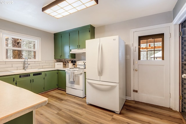 kitchen with under cabinet range hood, green cabinetry, a sink, and white appliances