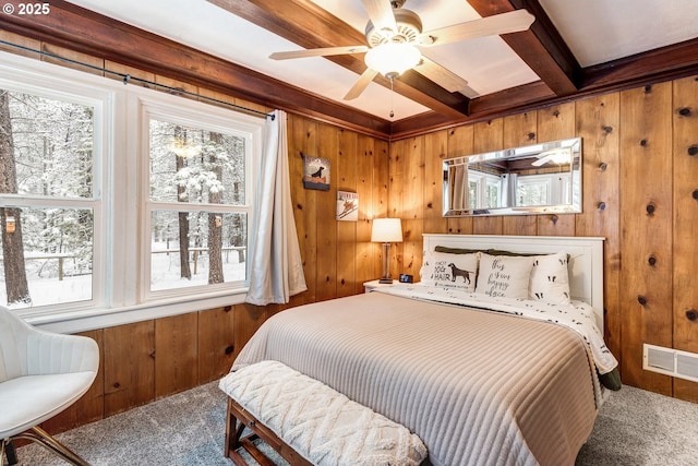 bedroom with wooden walls, carpet, and beam ceiling