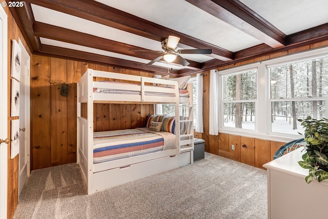 carpeted bedroom featuring beam ceiling and wood walls