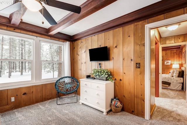 living area with beamed ceiling, carpet floors, and wood walls