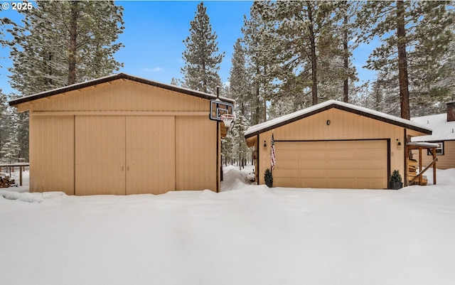 snow covered property with a garage and an outdoor structure