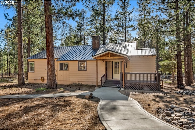 view of front of home featuring a chimney, a standing seam roof, metal roof, and a wooden deck