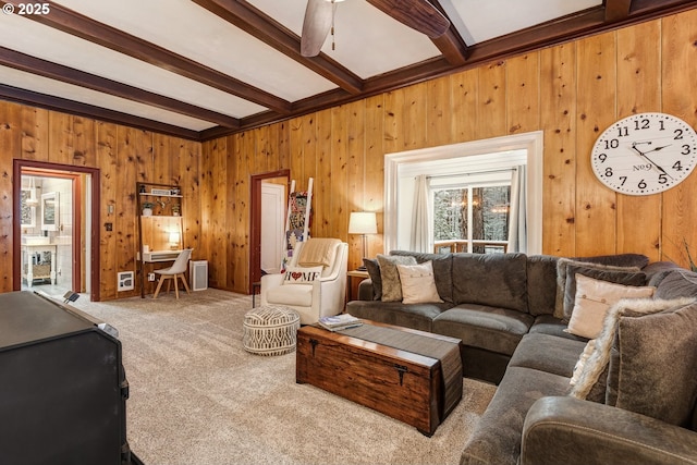 living room featuring wooden walls, beamed ceiling, and carpet flooring