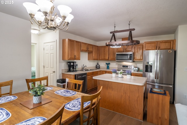 kitchen featuring a sink, light countertops, appliances with stainless steel finishes, a notable chandelier, and a center island